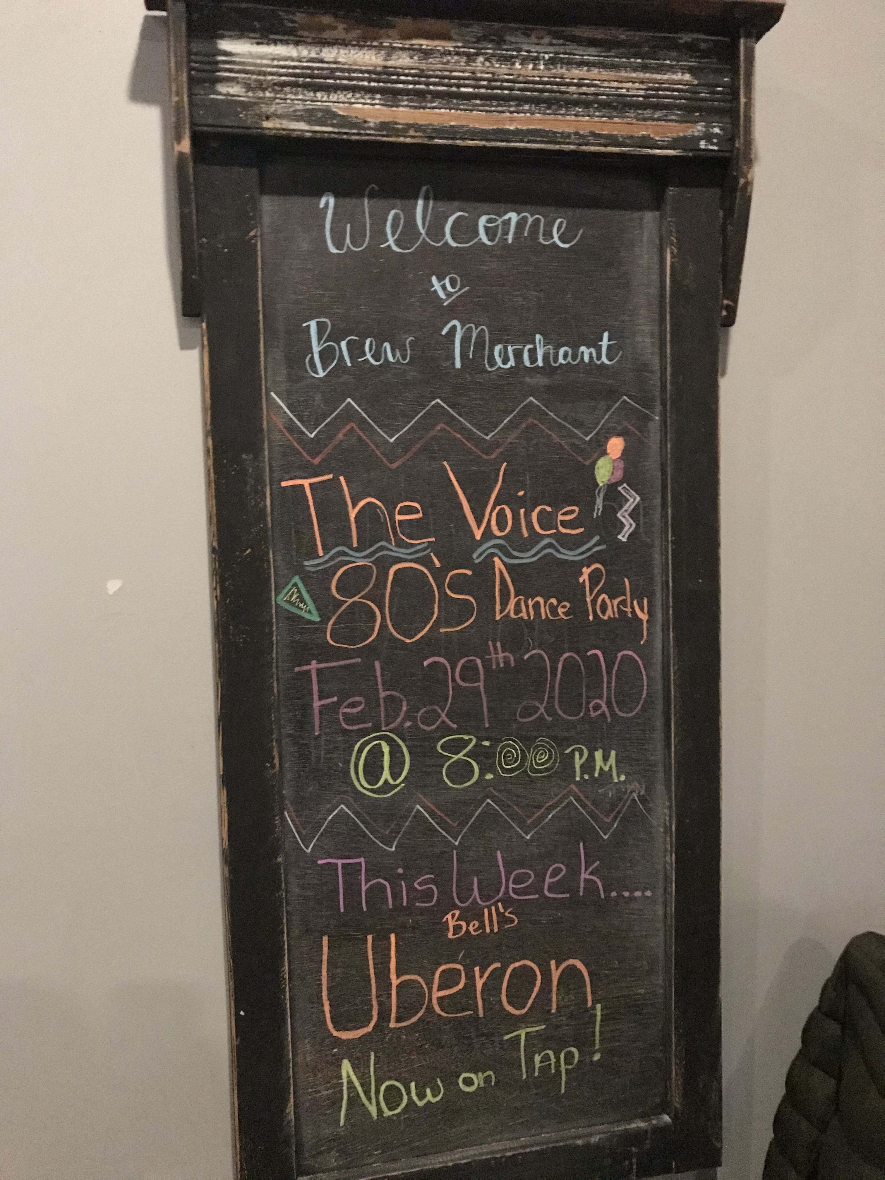 A+chalkboard+at+Brew+Merchant+advertising+an+80s+Dance+Party%2C+with+performance+by+The+Voice