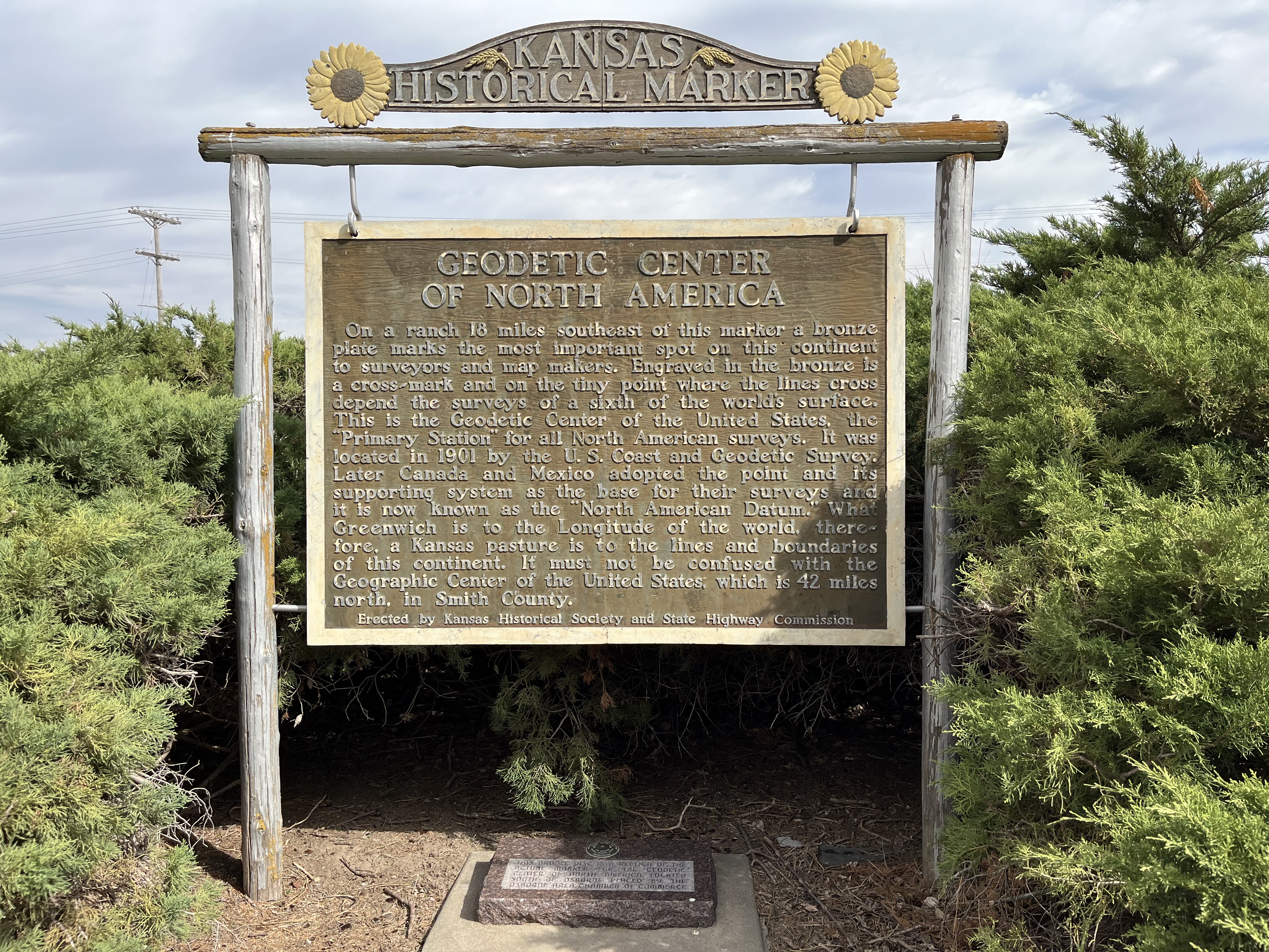 A+historical+marker+explaining+the+Geodetic+center+of+North+America.+It+says%3A+On+a+ranch+18+miles+southeast+of+this+marker+a+bronze+plate+marks+the+most+important+spot+on+this+continent+to+surveyors+and+map+makers.+Engraved+in+the+bronze+is+a+cross-mark+and+on+the+tiny+point+where+the+lines+cross+depend+the+surveys+of+a+sixth+of+the+world%E2%80%99s+surface.+This+is+the+Geodetic+Center+of+the+United+States%2C+the++%22Primary+Station%22+for+all+North+American+surveys.+It+was+located+in+190l+by+the+U.S.+Coast+and+Geodetic+Survey.+Later+Canada+and+Mexico+adopted+the+point+and+its+supporting+system+as+the+base+for+their+surveys+and+it+is+now+Known+as+the+%22North+American+Datum.%22+What+Greenwich+is+to+the+Longitude+of+the+world%2C+therefore%2C+a+Kansas+pasture+is+to+the+lines+and+boundaries+of+this+continent.+It+must+not+be+confused+with+the+Geographic+Center+of+the+United+States%2C+which+is+42+miles+north%2C+in+Smith+County.%0A++Erected+by+Kansas+Historical+Society+and+State+Highway+Commission
