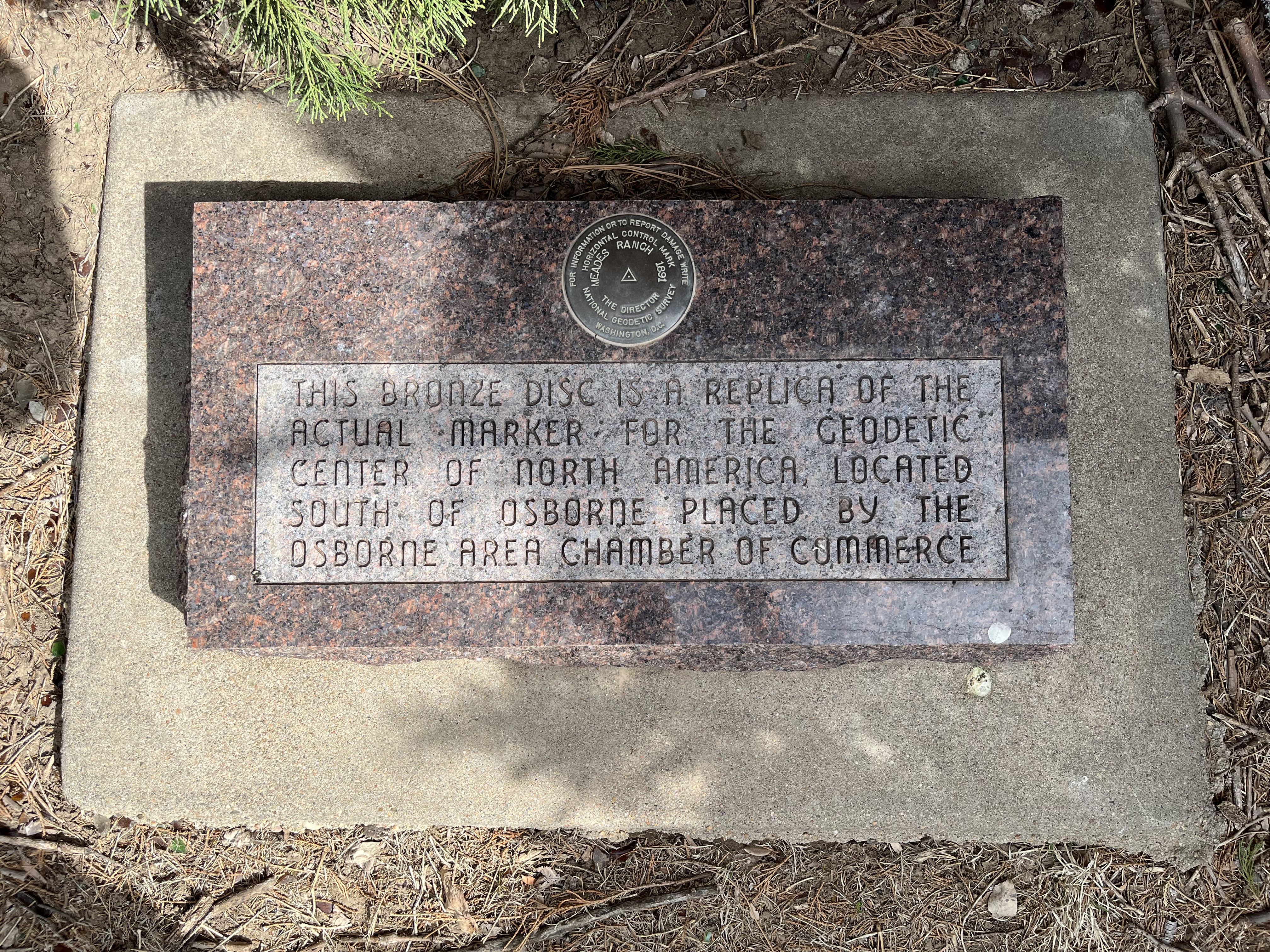 A+granite+block+with+a+bronze+disc+towards+the+top+center.+The+disc+says%3A+%22For+information+or+to+report+damage+write%0AThe+Director%0ANational+Geodetic+Survey%0AWashington%2C+D.C.%0A%0AHorizontal+control+mark%0AMeades+Ranch+1891%22%0ABeneath+the+disc+it+says%3A+%22This+bronze+disc+is+a+replica+of+the+actual+marker+for+the+Geodetic+Center+of+North+America%2C+located+south+of+Osborne.+Placed+by+the+Osborne+Area+Chamber+of+Commerce%22